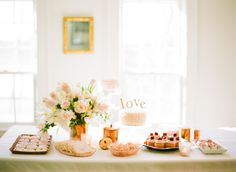 a table topped with cakes and desserts next to two large windowed windows in a white walled room