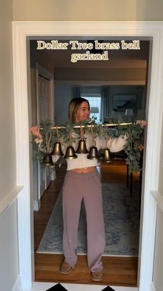 a woman standing in front of a doorway with bells on her head and the words dollar trees brass bell garland