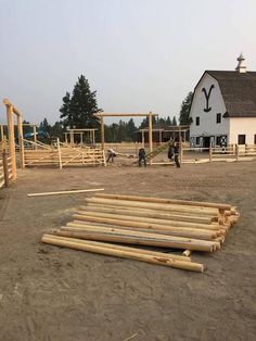 some people are working in the yard with wooden boards and poles on the ground next to a barn