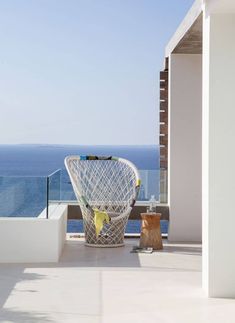 a white chair sitting on top of a balcony next to the ocean