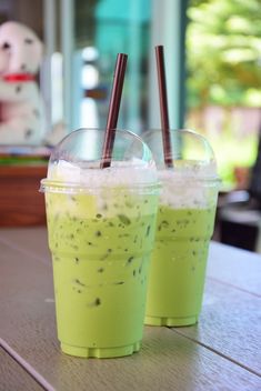 two plastic cups with straws in them sitting on a table