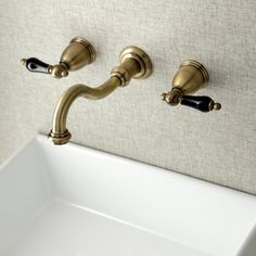 a bathroom sink with two faucets on the wall