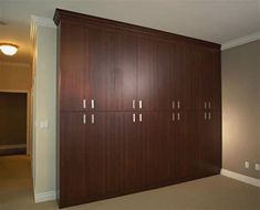 an empty room with wooden cabinets and carpeted flooring in the center, along with two lamps on either side of the wall