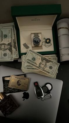 an open laptop computer sitting on top of a table next to money and other items