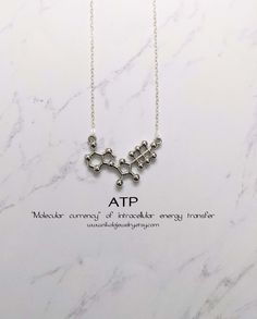 "ATP Molecule Necklace. The Adenosine triphosphate (ATP) molecule is the nucleotide known in biochemistry as the \"molecular currency\" of intracellular energy transfer; that is, ATP is able to store and transport chemical energy within cells. ATP also plays an important role in the synthesis of nucleic acids. Purchase includes an informational card, natural jewelry box and gift packaging. Gift? Add-on a hummingbird card for $7: https://www.etsy.com/listing/202506976/nikola-jewelry-hummingbird-c Physics Jewelry, Science Jewelry Biology, Science Necklace, Hummingbird Card, Biology Gifts, Molecule Jewelry, Chemistry Necklace, Adenosine Triphosphate, Biology Jewelry