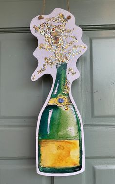 a green and yellow bottle hanging from a hook on a gray door with gold glitters