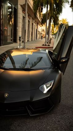 a black sports car parked in front of a building with its doors open and the hood up