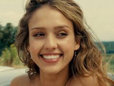 a close up of a person with a smile on her face and hair in the wind