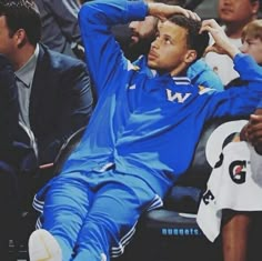 a man sitting on top of a basketball court next to other people in the stands