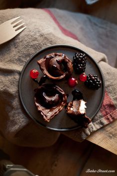 a plate topped with chocolate desserts on top of a table next to a knife and fork