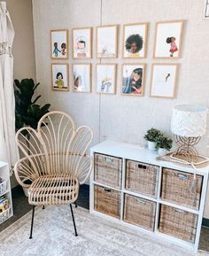 a wicker chair sitting next to a white cabinet in a room with pictures on the wall