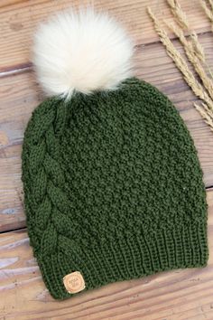 a green knitted hat with a white pom - pom