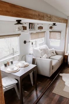 a living area with a couch, table and chairs in the corner next to a window