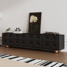 a living room with an entertainment center and rugs on the hardwood floor, in front of a white wall