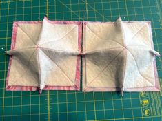 two pieces of fabric sitting on top of a cutting board next to a green mat