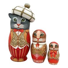 a cat figurine sitting next to two smaller cats wearing clothes and hats on top of each other