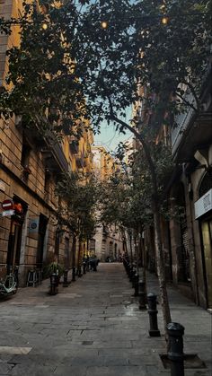 an empty street lined with tall buildings and trees in the middle of it's sidewalk