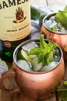 two copper mugs filled with ice and mint garnish next to a bottle of jameson