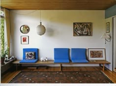 a living room with blue chairs and pictures on the wall