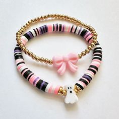 two bracelets with pink, black and white beads and a gold beaded dog charm