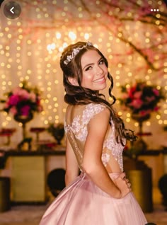 a woman in a pink dress smiling at the camera and wearing a tiara with flowers on it