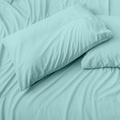 two pillows on top of each other in front of a blue bed sheet and pillowcase