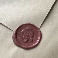 a wax stamp with a rose on it is laying on an open envelope that has been sealed