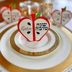 an apple shaped place setting with the names of two different languages on it and gold rimmed plates