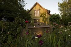 a house is surrounded by flowers and trees