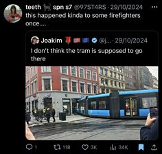 two people are taking pictures of a train on the street and one is holding a cell phone