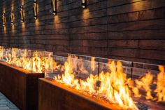 the fire is glowing brightly in front of the building's wall and benches on both sides