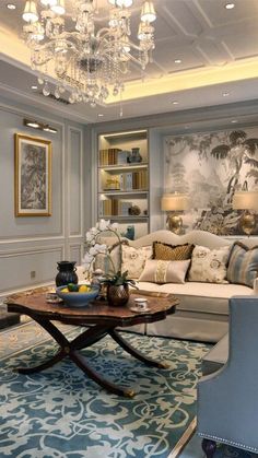 a living room filled with furniture and a chandelier hanging from the ceiling above