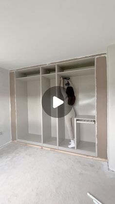 a person is standing in the middle of a room with white walls and shelving