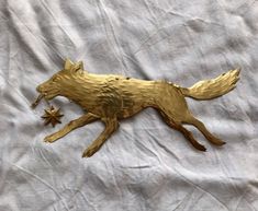 a golden metal dog with stars on it's tail and head is laying on a white sheet