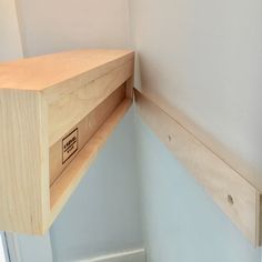 the corner of a room with a wooden shelf on one side and a closed drawer on the other