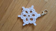 a crocheted snowflake keychain on a wooden floor with a pair of scissors