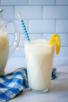 a pitcher of milk and a glass with a lemon slice on the rim next to it