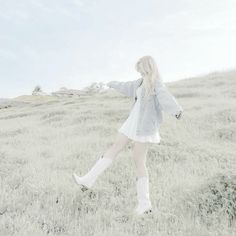 a woman walking across a grass covered field