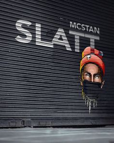 a street scene with a person wearing a helmet on the side of a building that has graffiti on it