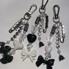 several key chains with charms attached to them on a white surface, one is black and the other is white