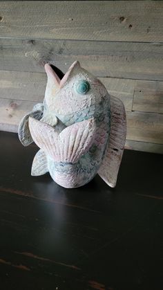 a ceramic fish sitting on top of a wooden table