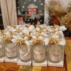 several small jars with flowers and pearls in them on a table next to a christmas tree