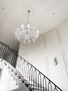 a chandelier hanging from the ceiling in a room with white walls and metal railings