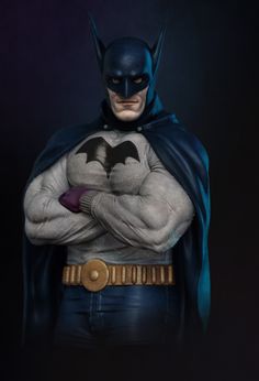 the batman statue is posed with his hands on his chest and arms crossed, in front of a dark background