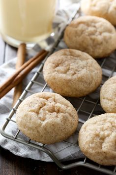 cinnamon sugar cookies cooling on a wire rack with cinnamon sticks next to it and a glass of orange juice in the background