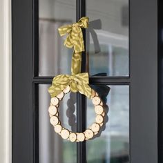 a wreath hanging on the front door of a house with wood slices and ribbon tied around it