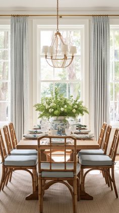 a dining room table with blue chairs and a chandelier hanging from the ceiling