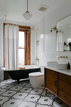 a bath room with a toilet a sink and a bath tub next to a window