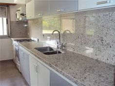 a kitchen with granite counter tops and white cabinets, along with stainless steel sink faucets