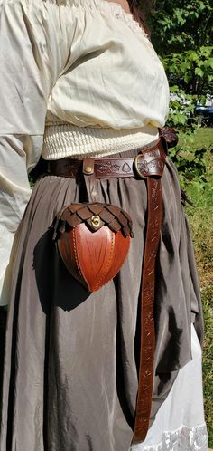 a woman wearing a brown leather belt with a heart shaped bag on it's back